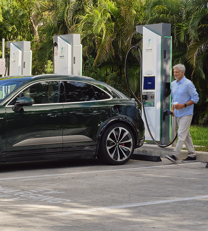 View of an EV charging at at an Electrify America station with the vehicle's owner.
