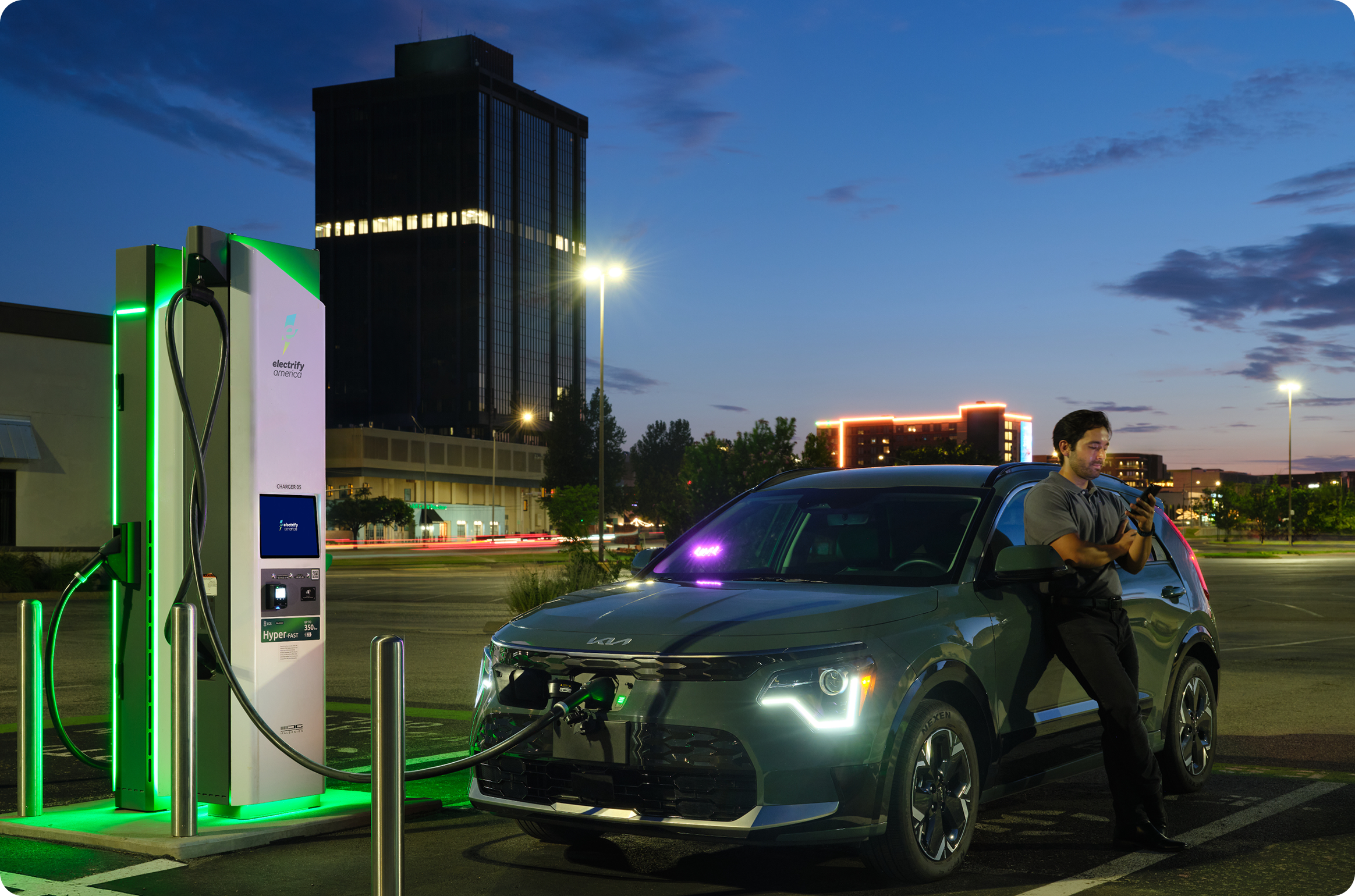 Man charging his vehicle at an Electrify America charger