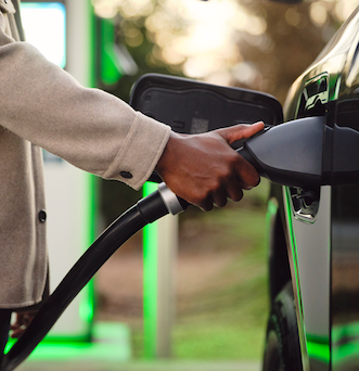 Woman using mobile device near an Electrify America charging station