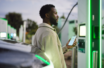 Woman using her phone to pay at an Electrify America charging station