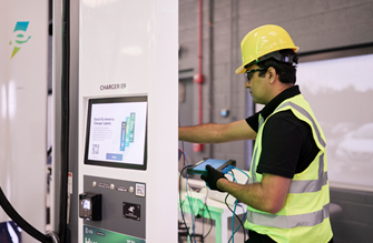 A worker prepares to charge an electric bus using an Electrify America charger